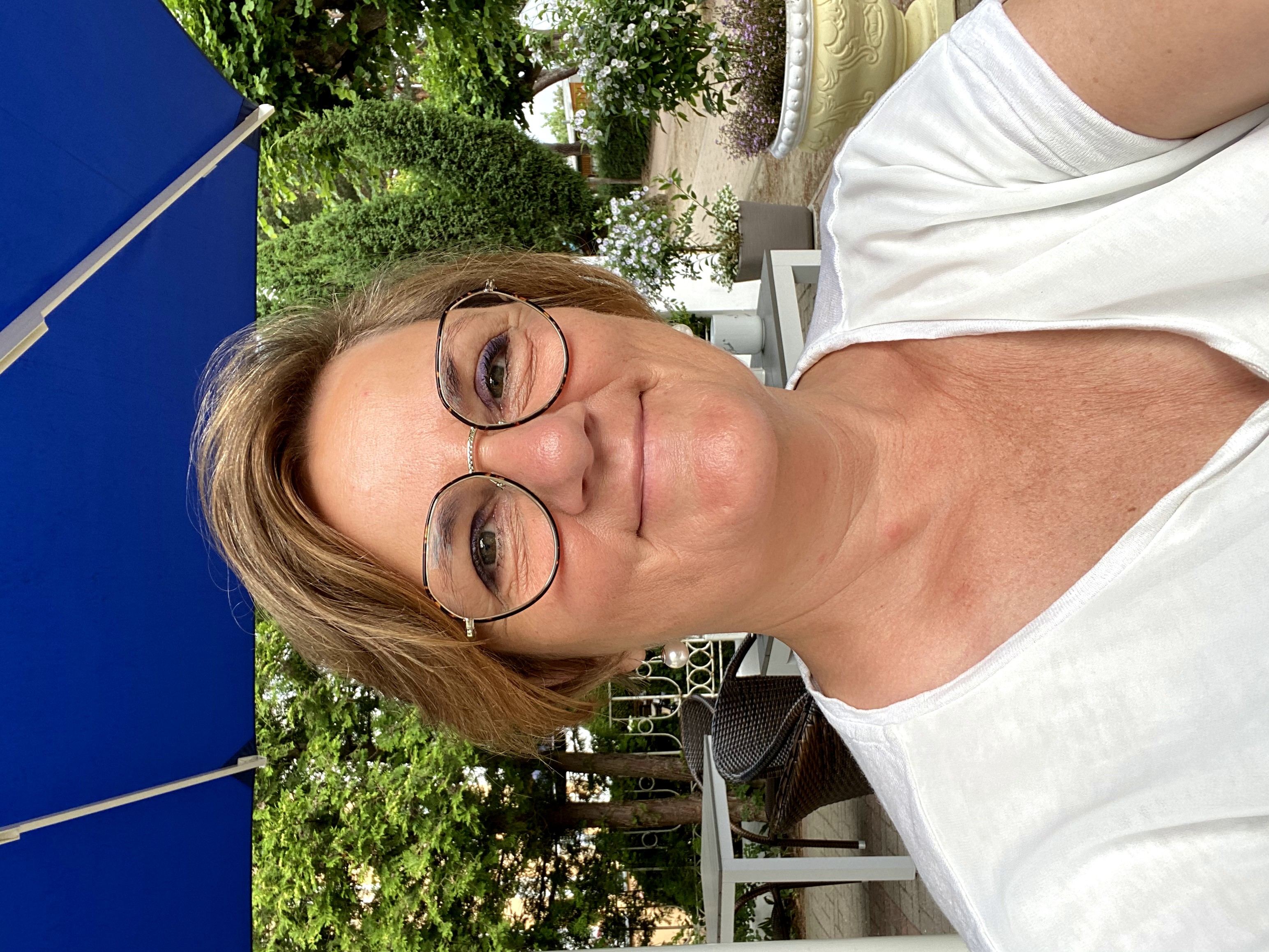Dagmar auf Stuhl mit blauem Schirm auf Frühstücksterrasse